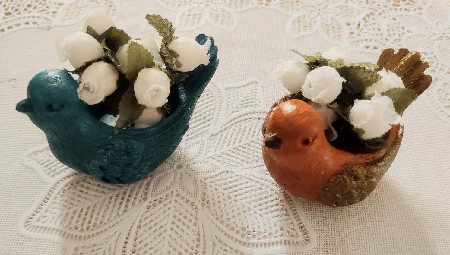 Passarinhos decorativos em gesso, usados como mini vasos com flores brancas